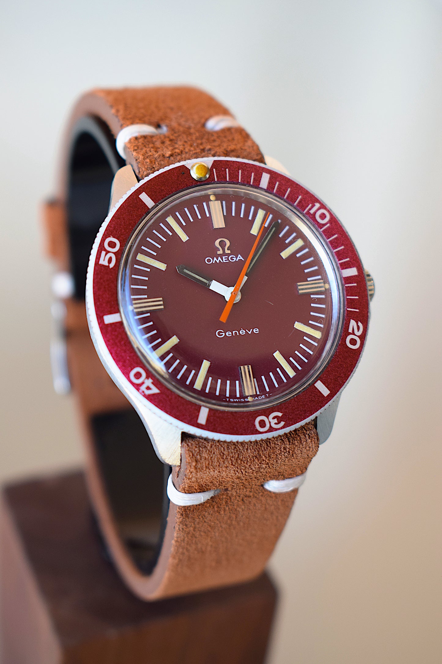 Omega watch with burgundy dial on a wooden stand