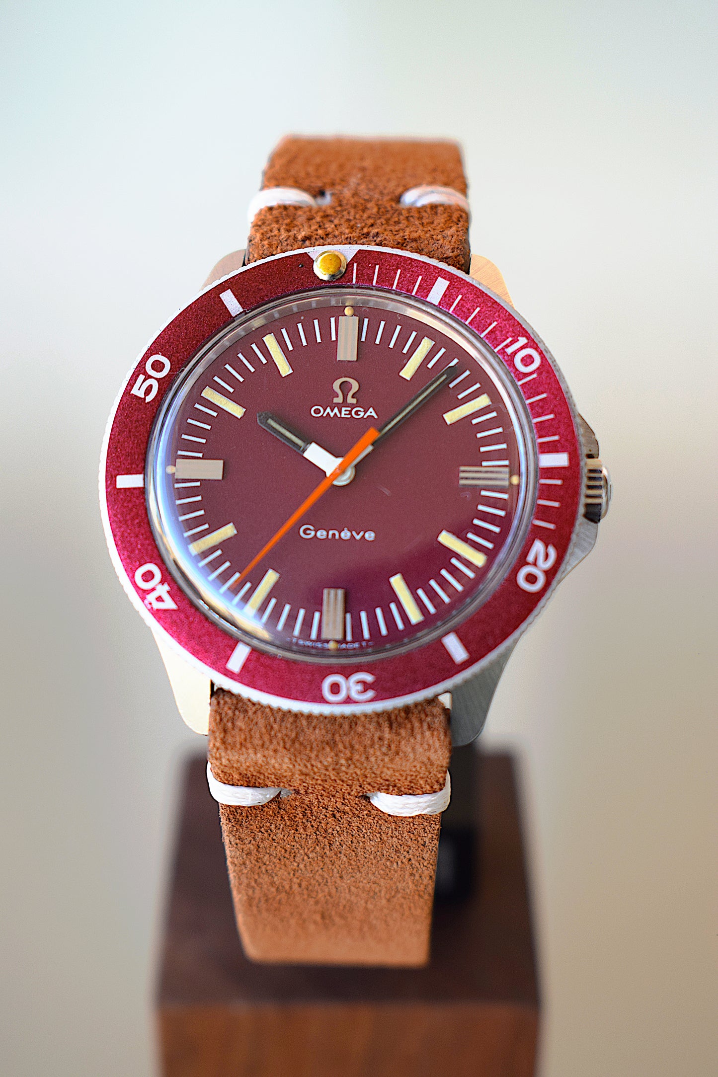 Omega watch with burgundy dial on a wooden stand