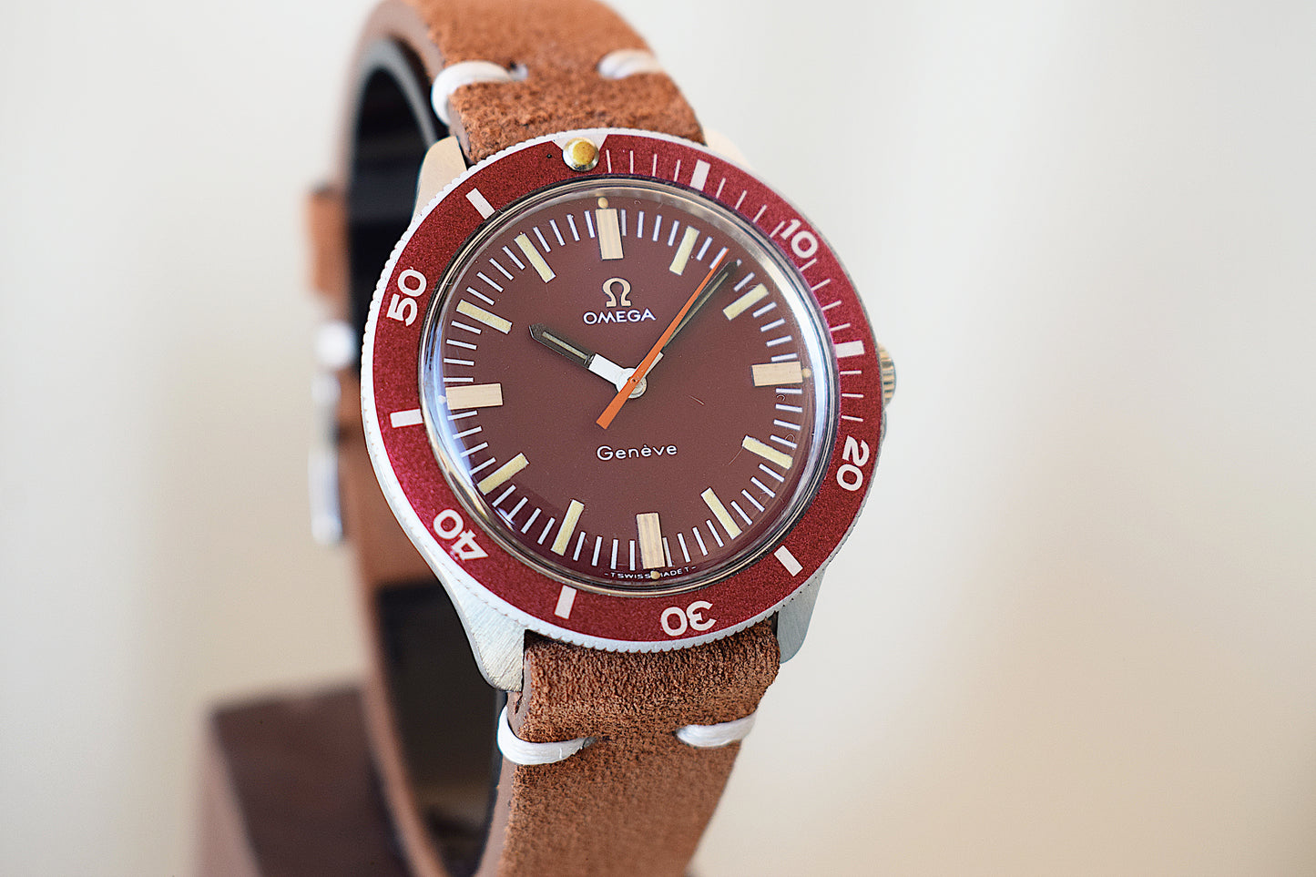 Omega watch with burgundy dial on a wooden stand
