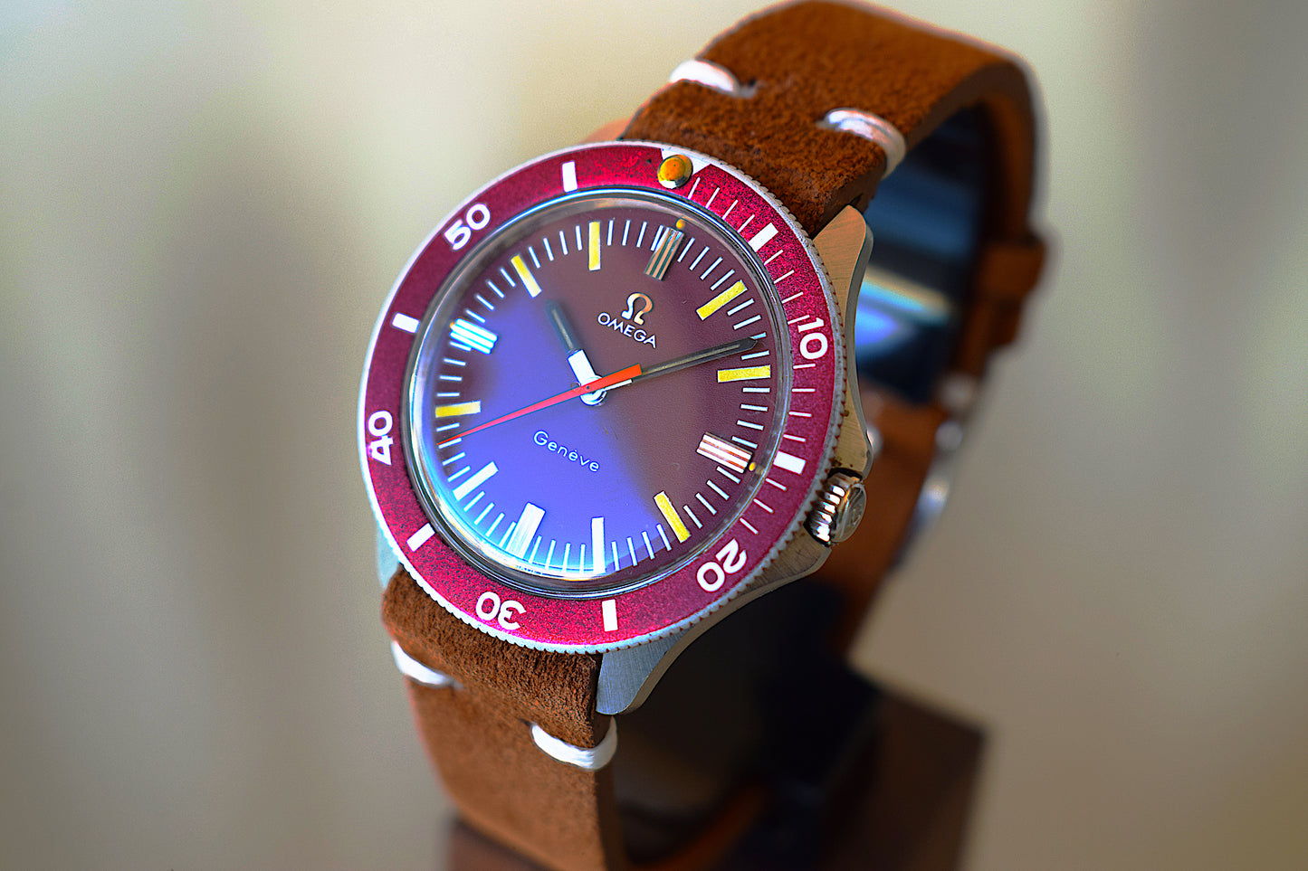 Omega watch with burgundy dial on a wooden stand